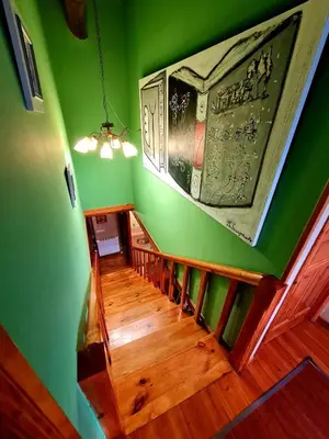 a green room with a staircase with a painting on the wall at A Pontiga I Casa Rural in Mezonzo
