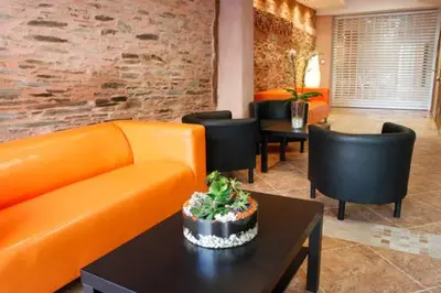 a living room with an orange couch and black chairs at Apartamentos Albariño in Vegadeo