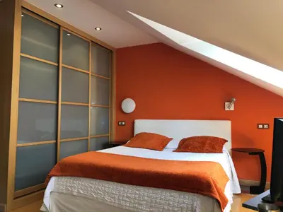 a bedroom with a bed with an orange wall at Apartamentos Albariño in Vegadeo