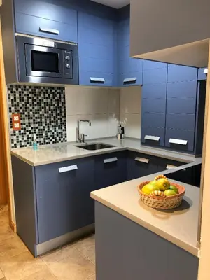a blue kitchen with a bowl of fruit on a counter at Apartamentos Albariño in Vegadeo