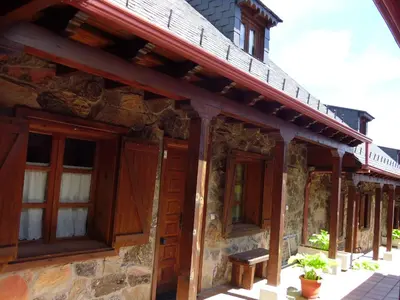 an old stone building with wooden doors and windows at Alojamientos Rurales El Fontano in Galende