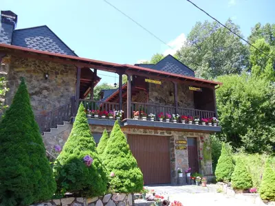 a house with a balcony with flowers on it at Alojamientos Rurales El Fontano in Galende