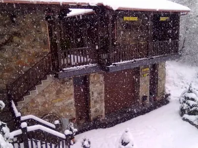a building in the snow with snow falling on it at Alojamientos Rurales El Fontano in Galende