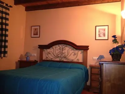 a bedroom with a bed with a blue bedspread at Alojamientos Rurales El Fontano in Galende