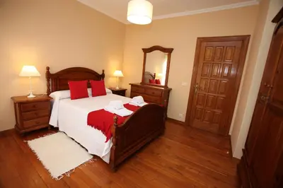 a bedroom with a bed with red pillows and a mirror at Casa Rubieira in Sequeiro