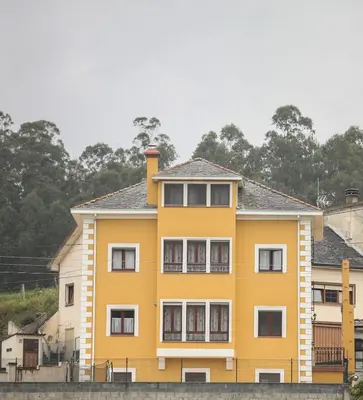 a yellow house with white windows and trees at Casa Rubieira in Sequeiro