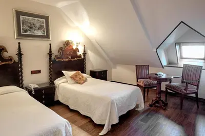 a bedroom with two beds and a table and chairs at Palacio Arias in Navia