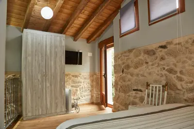 a bedroom with a bed and a stone wall at A Cucada in Sabariz