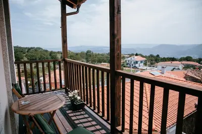 a wooden balcony with a table and a view at O balcón da ribeira in Parada del Sil