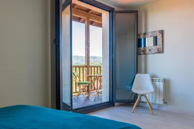 a bedroom with a door open to a balcony with a chair at O balcón da ribeira in Parada del Sil