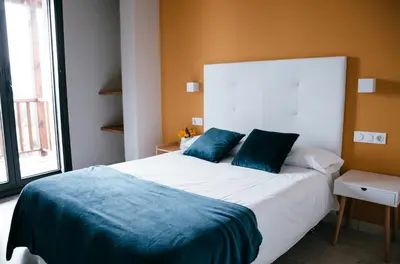 a bedroom with a large white bed with blue pillows at O balcón da ribeira in Parada del Sil