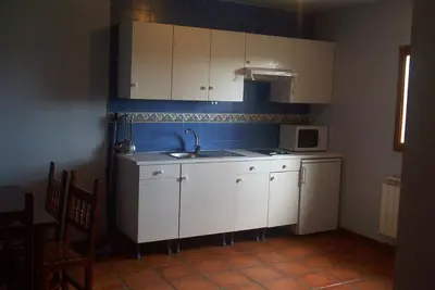 a kitchen with white cabinets and a sink and a microwave at Hotel Rural El Rincón de Trefacio in Trefacio