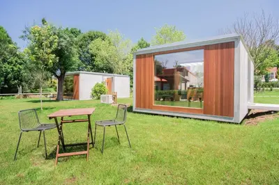 a small house with a table and chairs in the grass at Bungalow Camping Los Manzanos in Santa Cruz de Oleiros