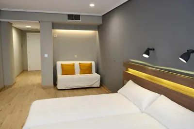 a bedroom with two white beds and two yellow pillows at Hotel Alda Sada Marina in Sada