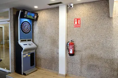 a video game machine next to a wall with a fire extinguisher at Hotel Alda Sada Marina in Sada