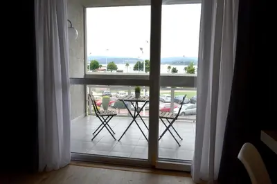 a room with a large window with a table on a balcony at Hotel Alda Sada Marina in Sada