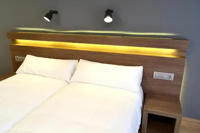 a bed with a wooden headboard and two pillows at Hotel Alda Sada Marina in Sada