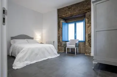 a bedroom with a bed and a chair and a window at Montebreamo in Puentedeume