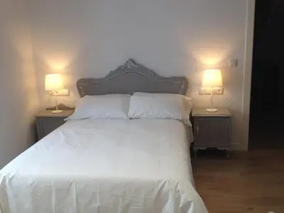 a bedroom with a white bed with two lamps at Montebreamo in Puentedeume