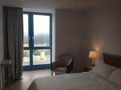 a bedroom with a bed and a chair and a window at Montebreamo in Puentedeume