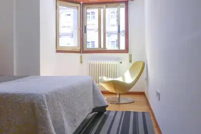 a bedroom with a chair and a bed and a window at RyS Ourense Centro PARKING Gratis in Ourense