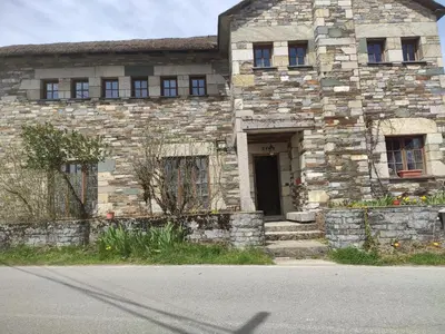 an old stone building with a door on a street at Albergueria Frade in O Cebreiro