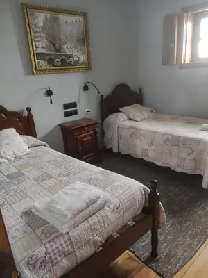 a bedroom with two beds and a picture on the wall at Albergueria Frade in O Cebreiro