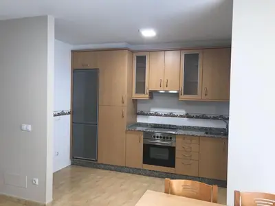 an empty kitchen with wooden cabinets and appliances at Apartamento Good Way in O Pedrouzo