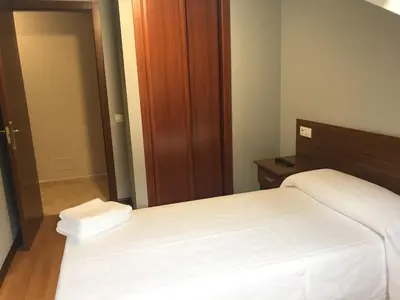 a bedroom with a white bed and a wooden door at Apartamento Good Way in O Pedrouzo