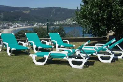 a group of green and white chairs sitting on the grass at Alojamientos Viveiro - El Escairo in Viveiro