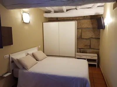 a bedroom with a white bed and a stone wall at Aldea Rural A Cortiña in Pepín