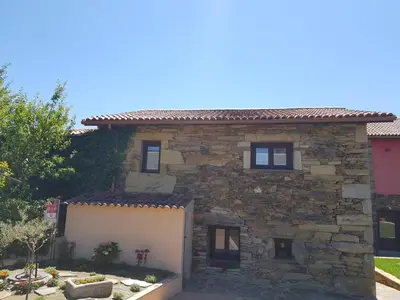 a stone house with a white garage at Aldea Rural A Cortiña in Pepín