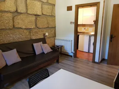 a living room with a couch and a stone wall at Aldea Rural A Cortiña in Pepín