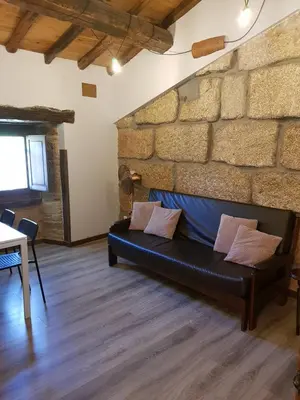 a black couch in a room with a brick wall at Aldea Rural A Cortiña in Pepín
