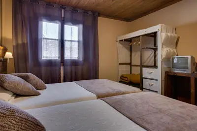 a bedroom with two beds and a tv and a window at Aldea Rural A Cortiña in Pepín