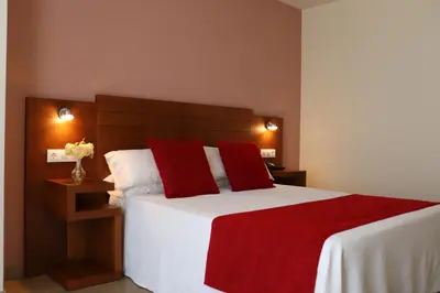 a hotel room with a bed and a red chair at HOTEL ARZÚA in Arzúa