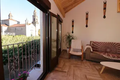 a living room with a balcony with a view of a church at A Casa das Burgas in Cuntis