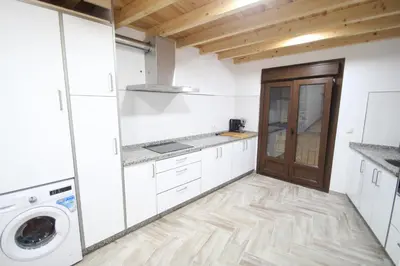 a kitchen with white cabinets and a wooden door at A Casa das Burgas in Cuntis
