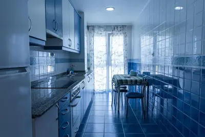 a blue kitchen with a sink and a table at Puente Romana in San Ciprián