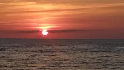a sunset over the ocean with the sun in the sky at Puente Romana in San Ciprián