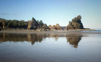a beach with some rocks in the water at A&L Playa in Viveiro