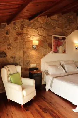 a bedroom with a bed and a chair at Casa do Cebro Casa con piscina y jacuzzi privados in Santiago de Compostela
