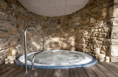 a stone bathroom with a hot tub in a stone wall at Casa do Cebro Casa con piscina y jacuzzi privados in Santiago de Compostela