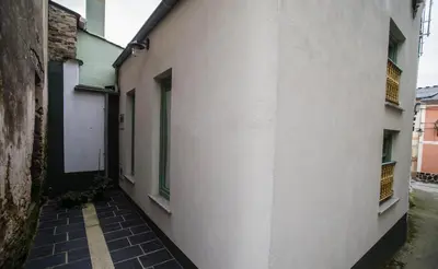 an alley with a white building and a window at Casa de Abaixo in Rinlo