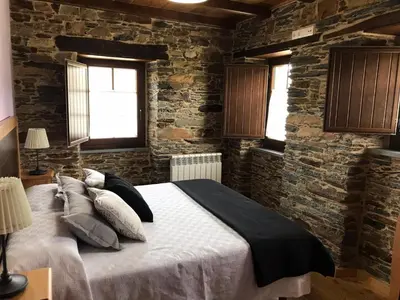 a bedroom with a large bed in a brick wall at Apartamentos Carola in San Tirso de Abres