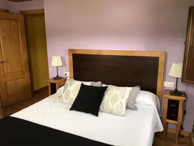 a bedroom with a large bed with white sheets and pillows at Apartamentos Carola in San Tirso de Abres