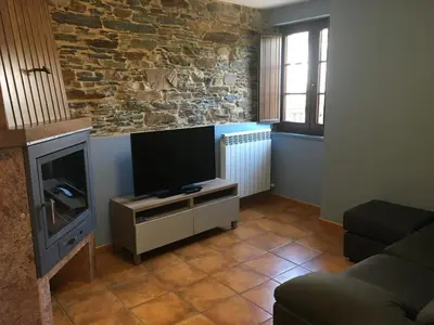a living room with a flat screen tv and a couch at Apartamentos Carola in San Tirso de Abres