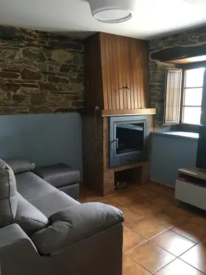 a living room with a couch and a television at Apartamentos Carola in San Tirso de Abres