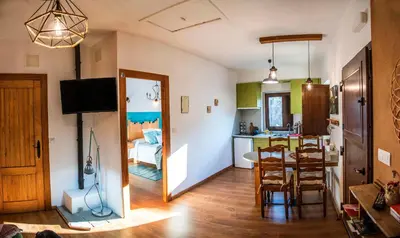 a living room with a dining room table and a kitchen at Fogar do Pumar in Pantón