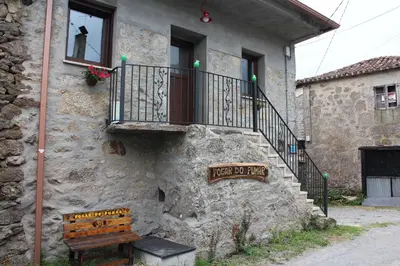 a stone building with a bench and a balcony at Fogar do Pumar in Pantón